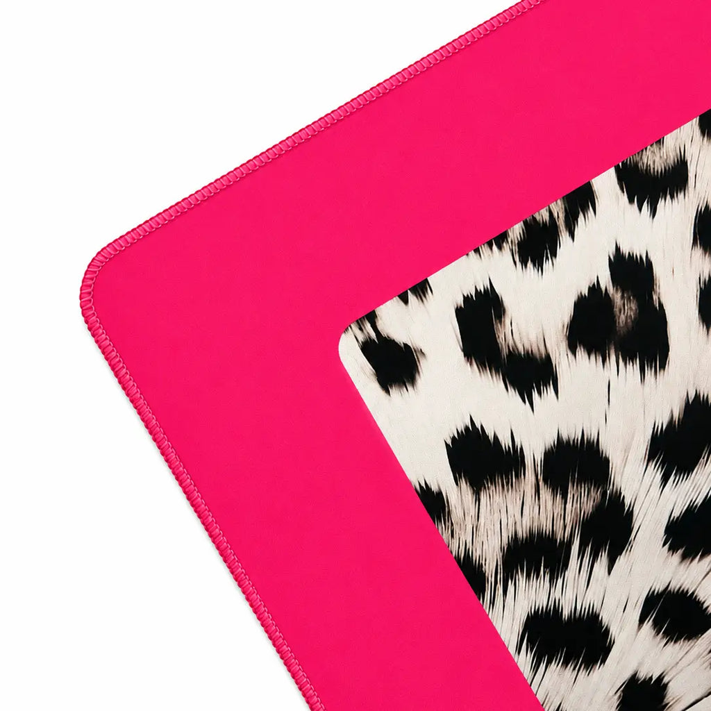 A close-up of a the corner of the mahjong mat that shows a bright hot pink stitched border around a white faux-hair surface with black leopard print.